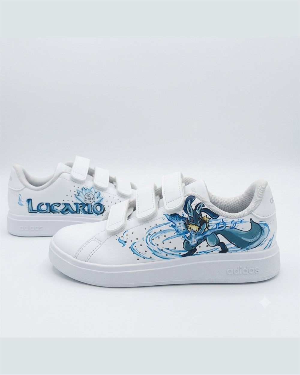 Paire d'Adidas customisée à la main avec le Pokémon Lucario, peinture bleue sur cuir blanc